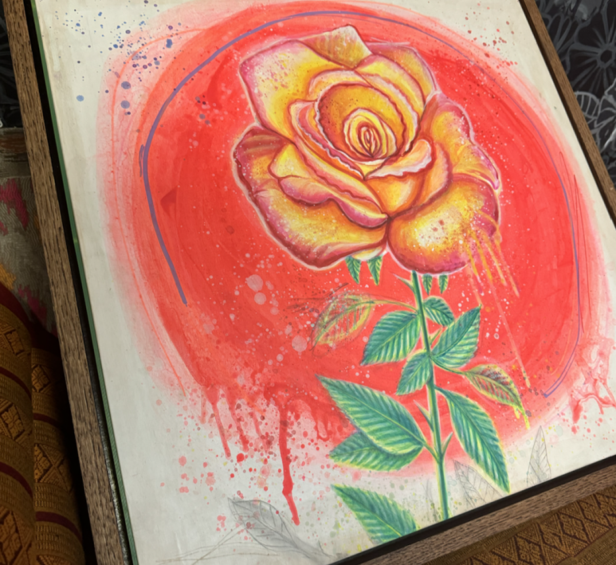 A wooden board painted with a rose, agaist a backdrop of dripping red paint