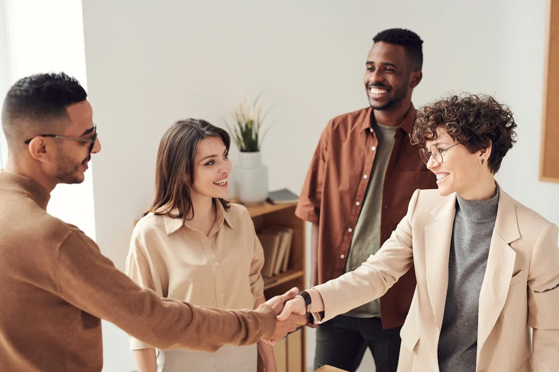 Four people in a room, with two shaking hands