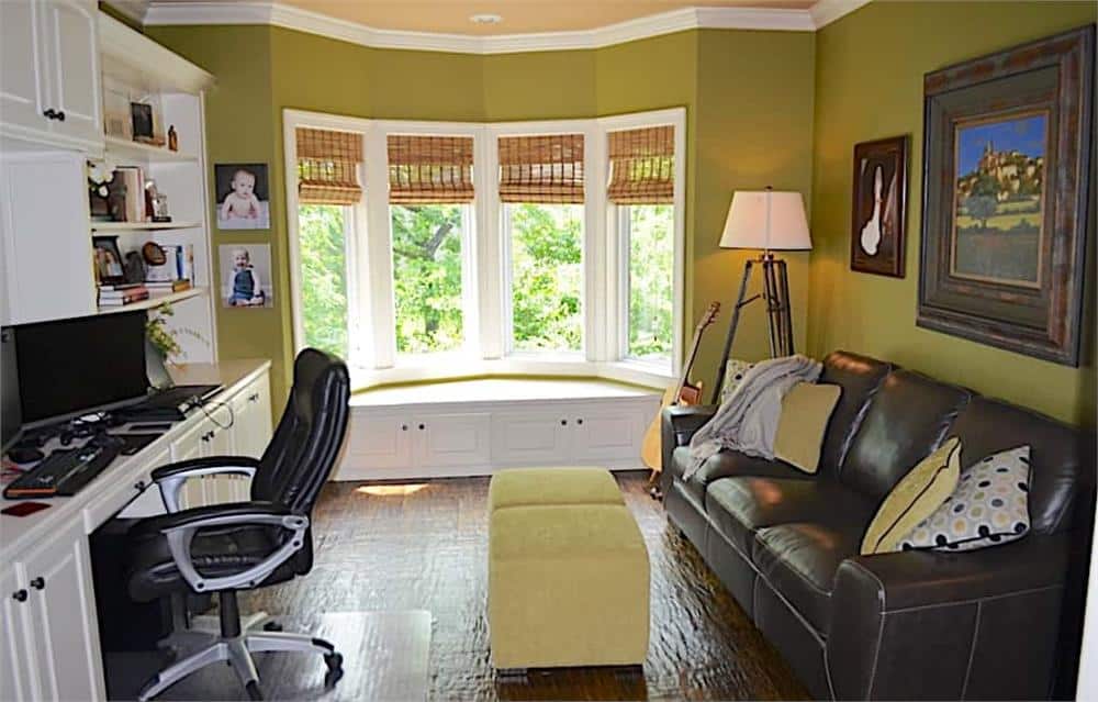 Study with a leather sofa, a white desk, and a bayed window seat.