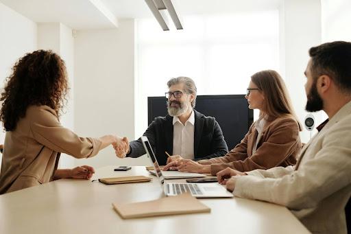 A person shaking hands with a person in a meeting Description automatically generated