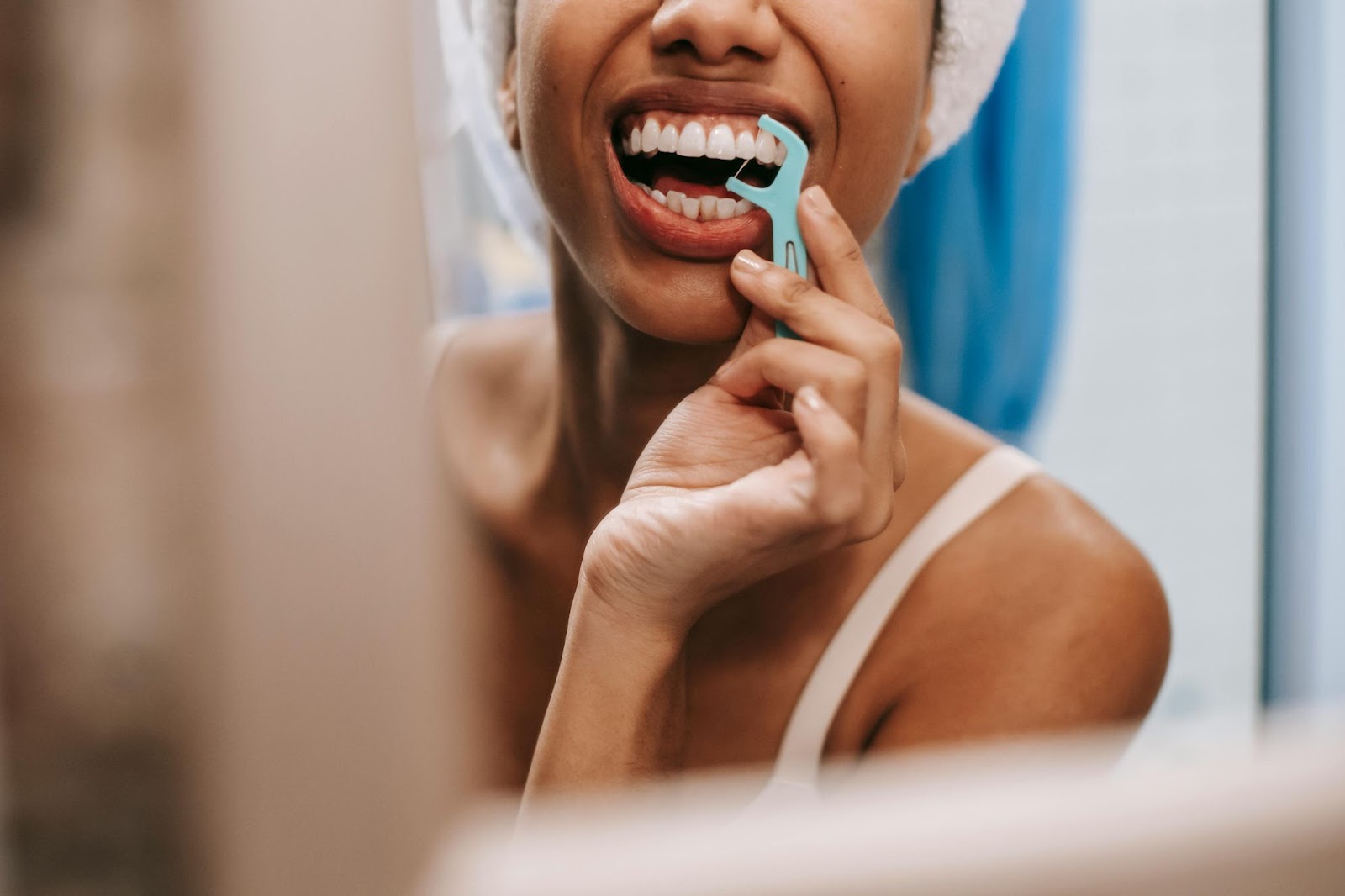 Woman flossing her teeth right out of the shower.