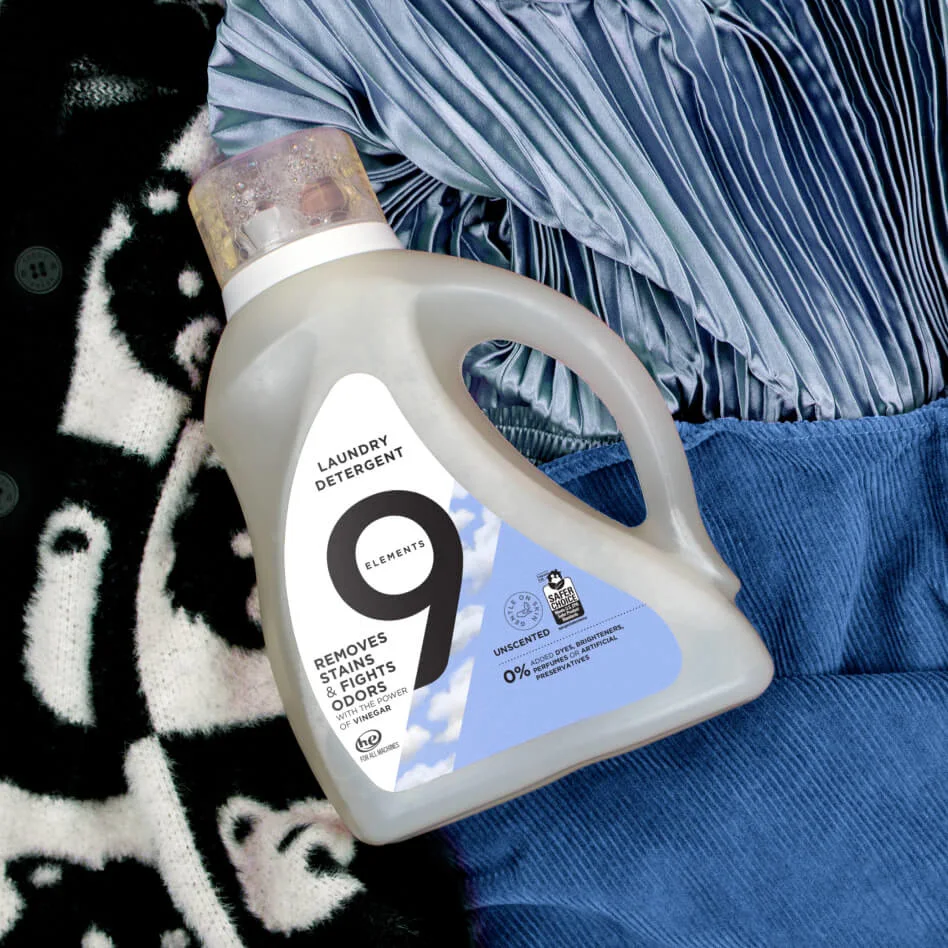 A 9 Elements Laundry Detergent bottle on a pile of different fabrics