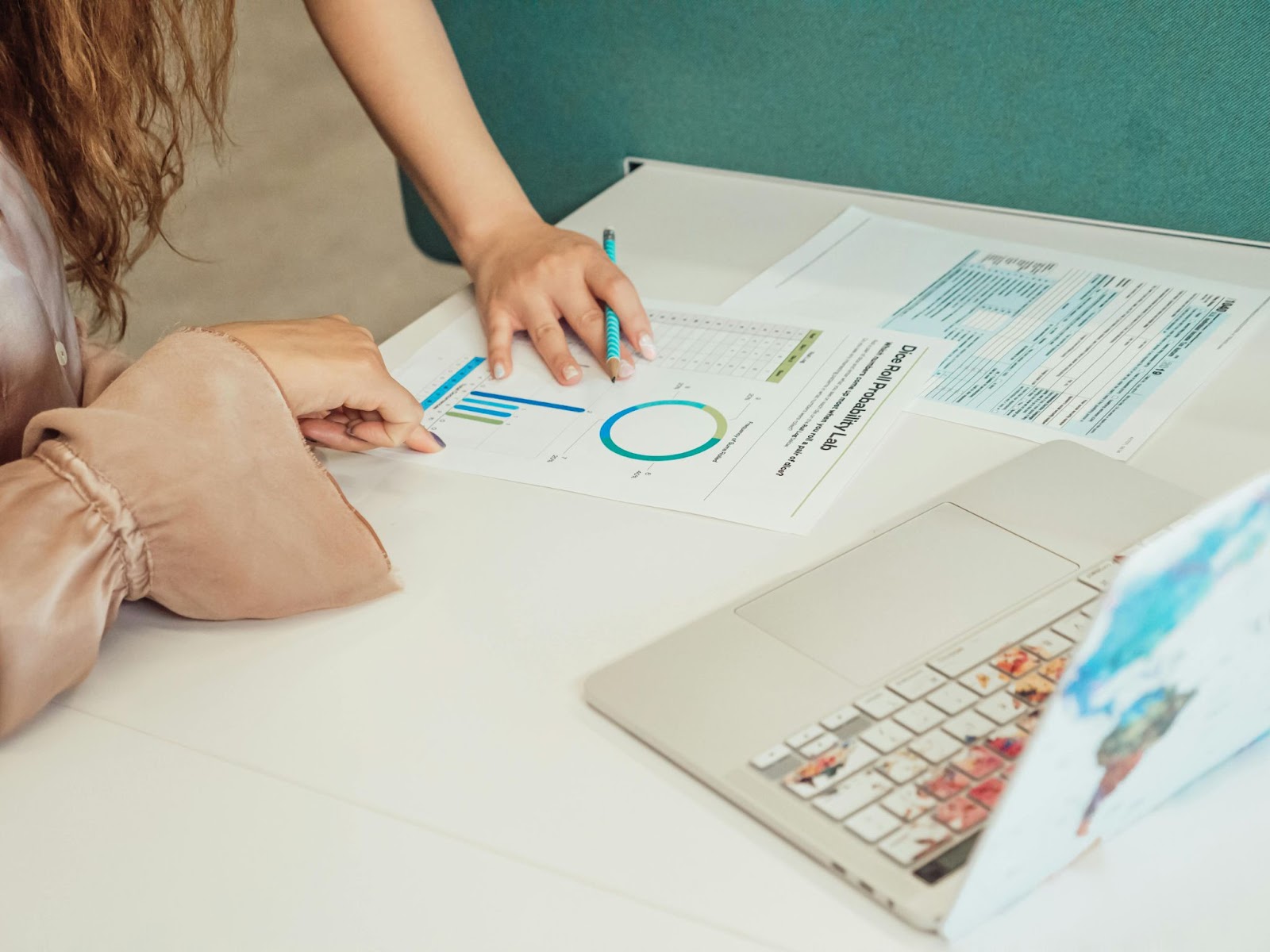 Mujer analiza datos en gráficos impresos usando software de gestión desde su laptop