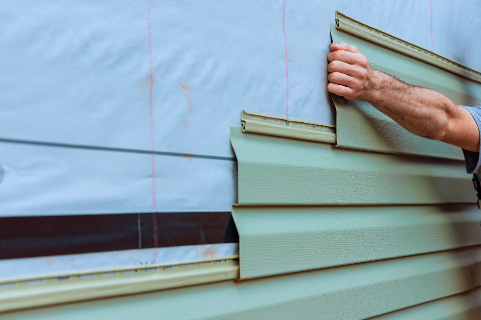 Man putting siding on a home. 