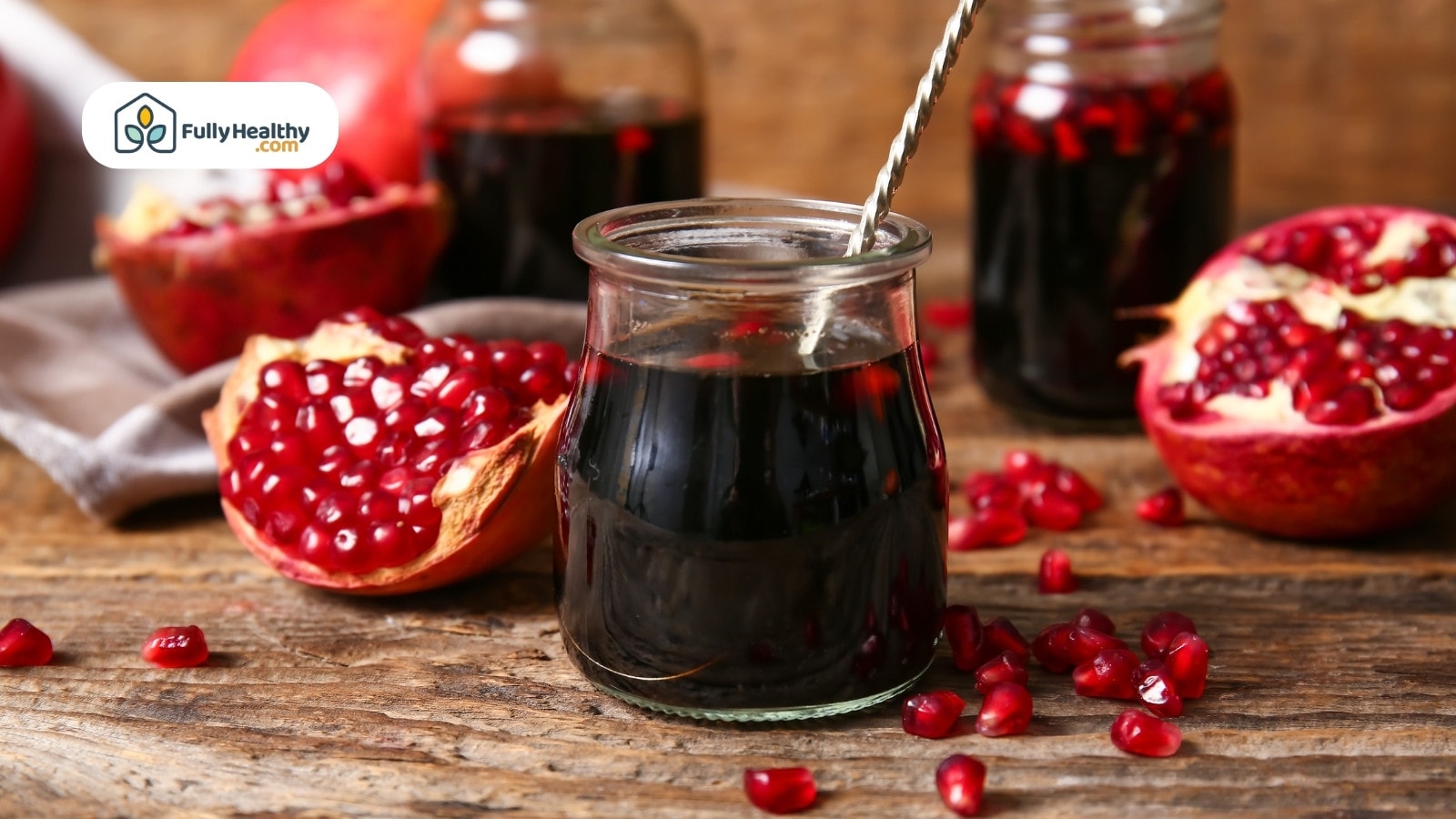 Pomegranate molasses in glass jar with fresh pomegranate seeds around