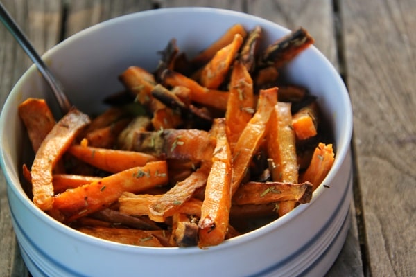 A white bowl filled with crispy air-fried sweet potato fries, lightly seasoned and served with a fork