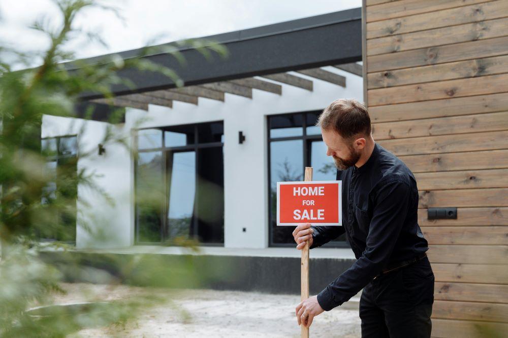 A man posting a sale sign for his home