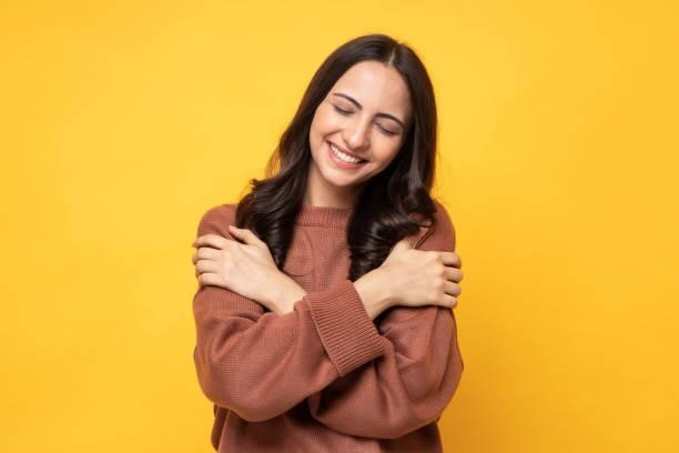 Photo of young women in winter wear standing on yellow background stock photo Photo of young women in winter wear standing on yellow background sweatshirts stock pictures, royalty-free photos & images