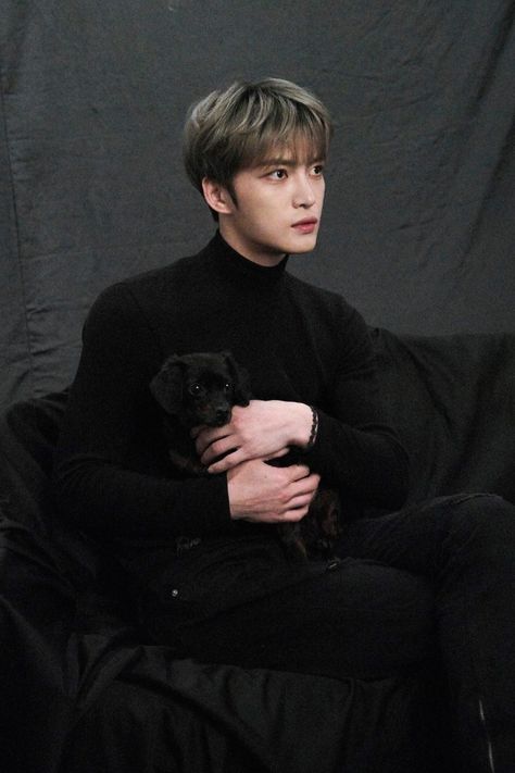 This containa Jaejoong sitting on a couch holding a black dog