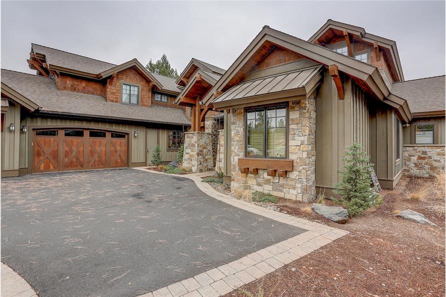 Angled front view showing the stone accents and side entry garage topped with a gable dormer.