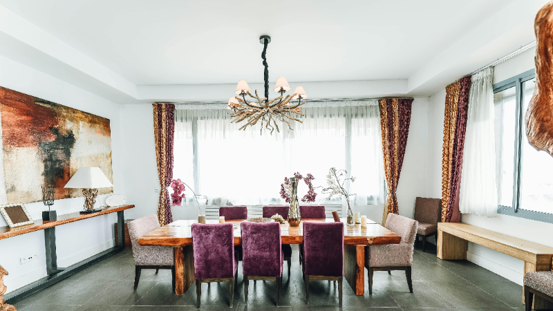 A rustic dining table under a chandelier