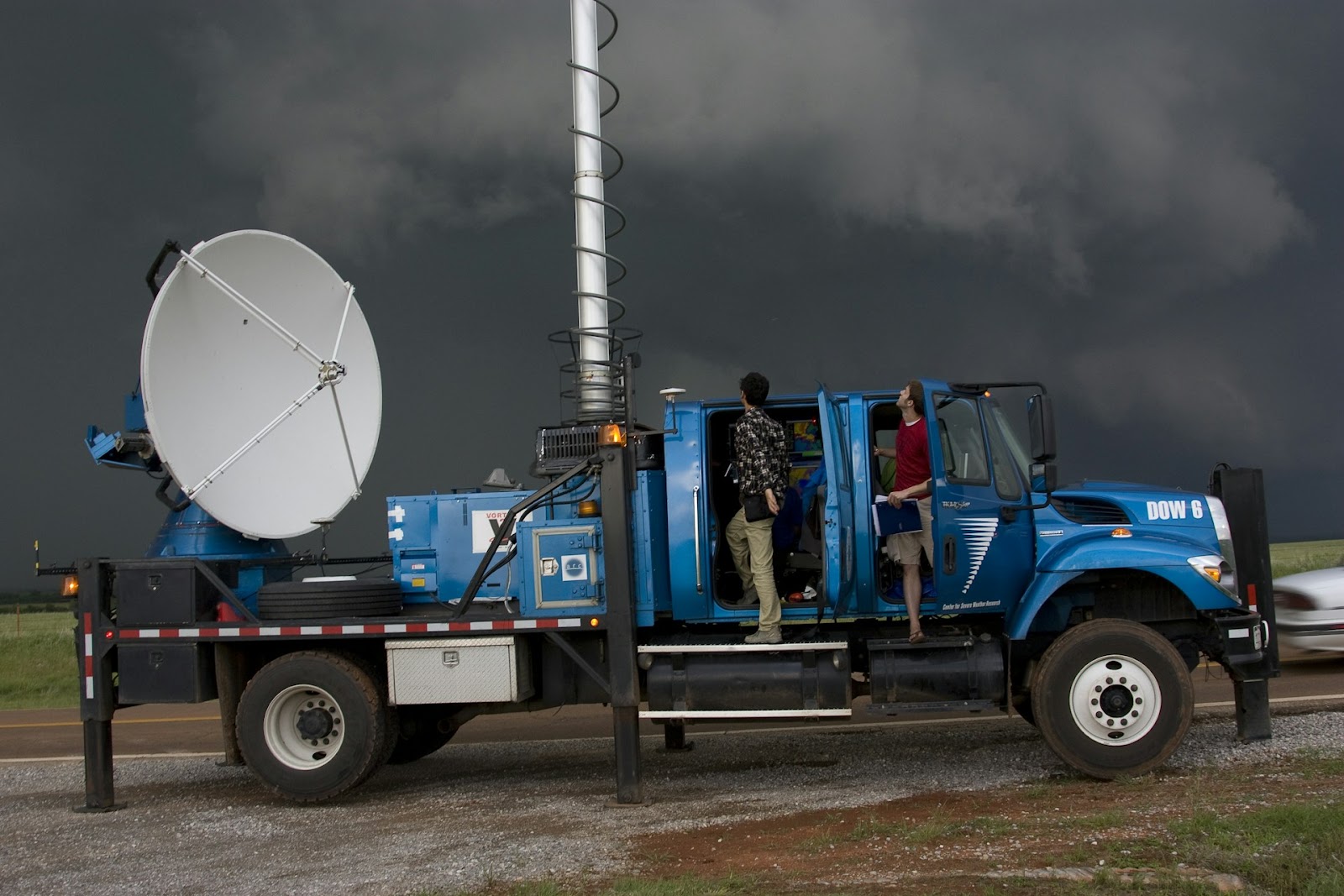 A large blue truck equipped with weather instruments, including a large satellite dish.