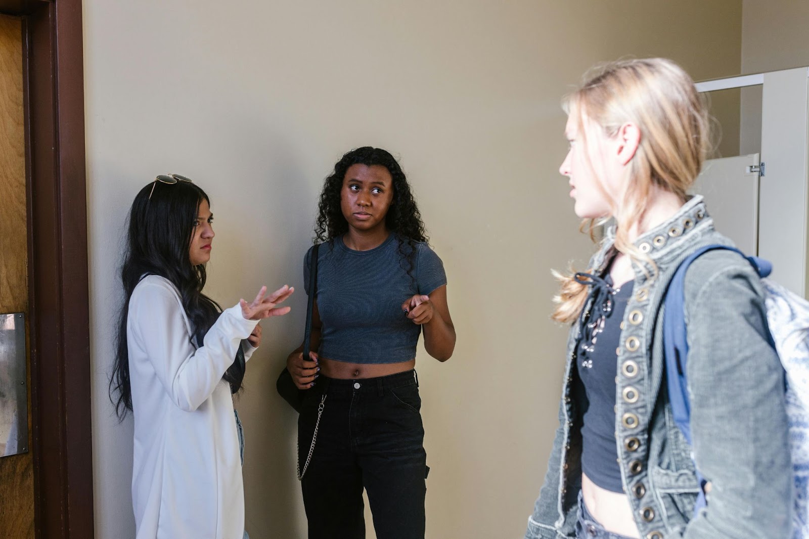 Two students pointing a finger at another one in a condescending way