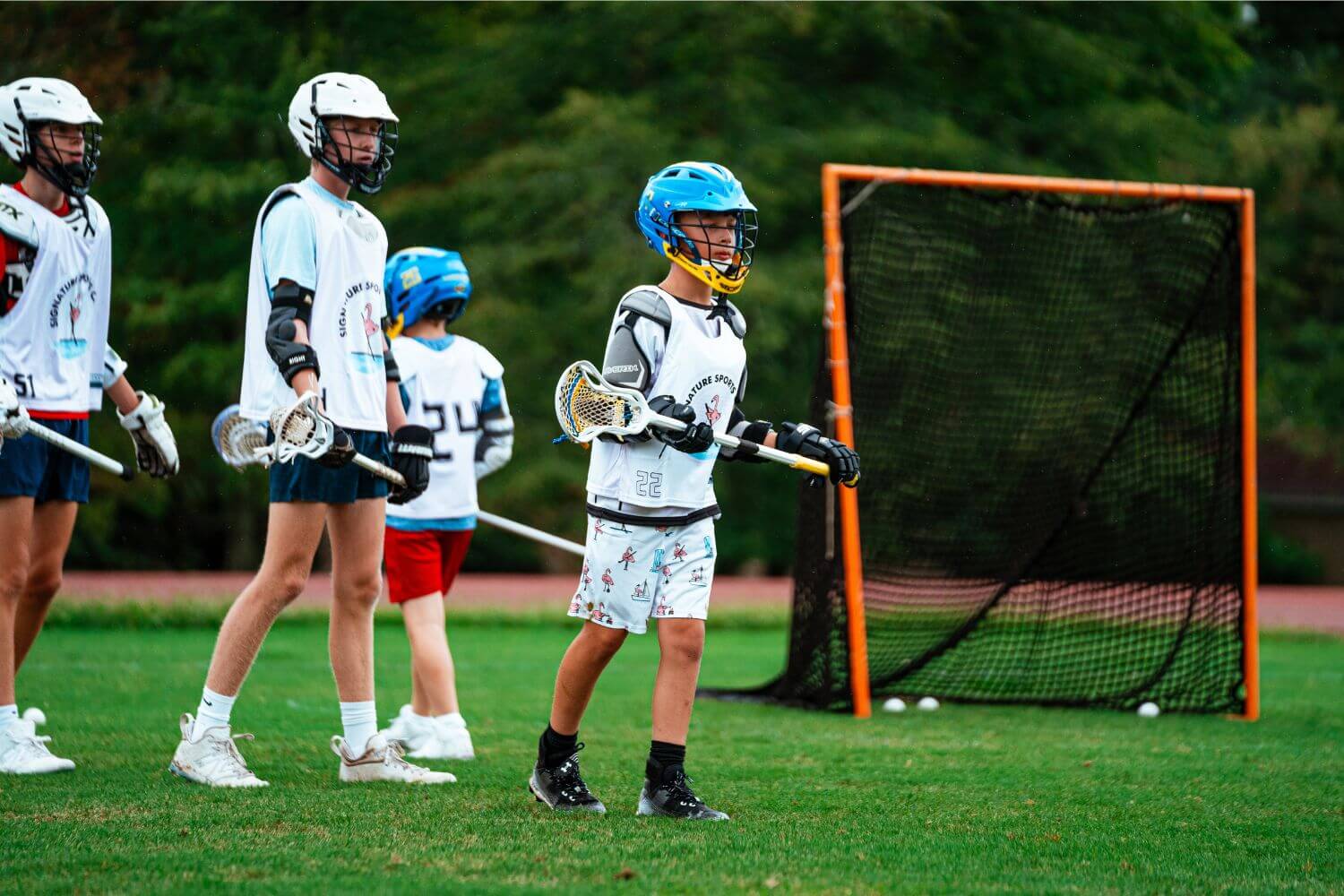 boys in lacrosse gear on the field during summer sports camp