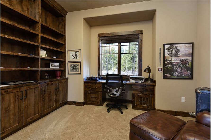 Study with wooden built-ins, a matching desk, and a leather lounge chair over the carpet flooring.