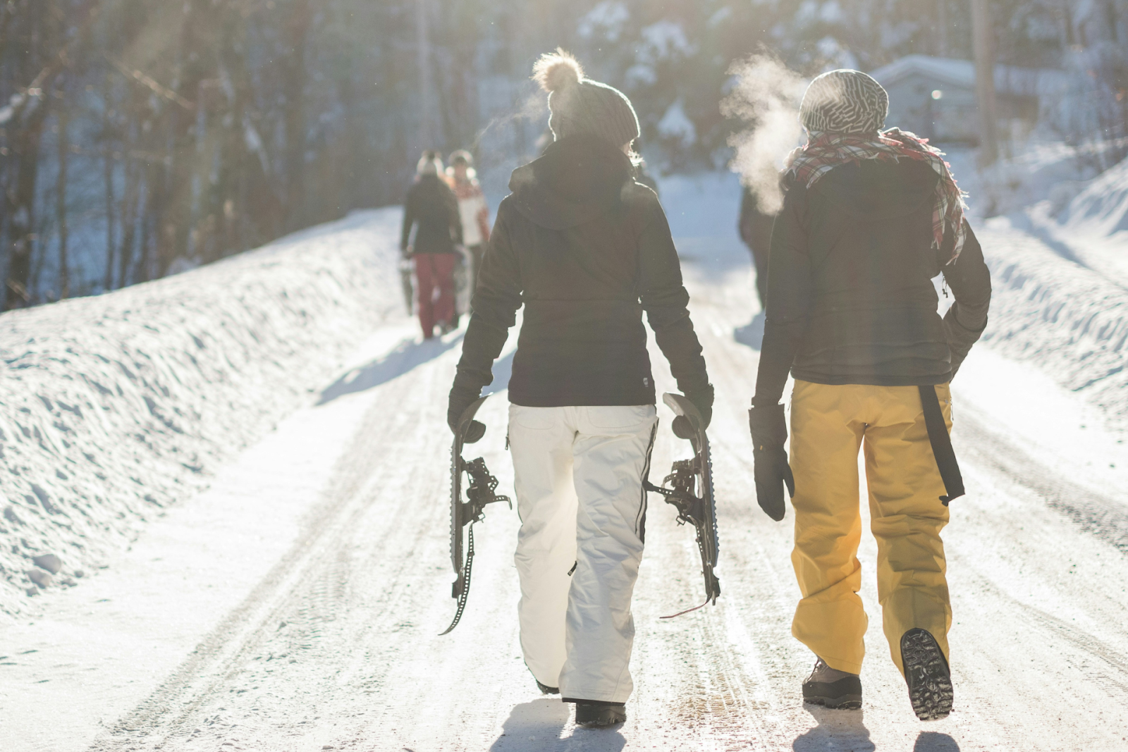 People holding snowshoes and walking down a snowy path