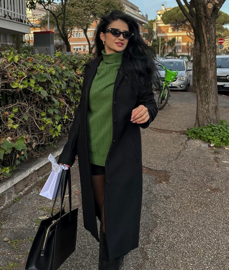 A black wool coat with a green sweater.