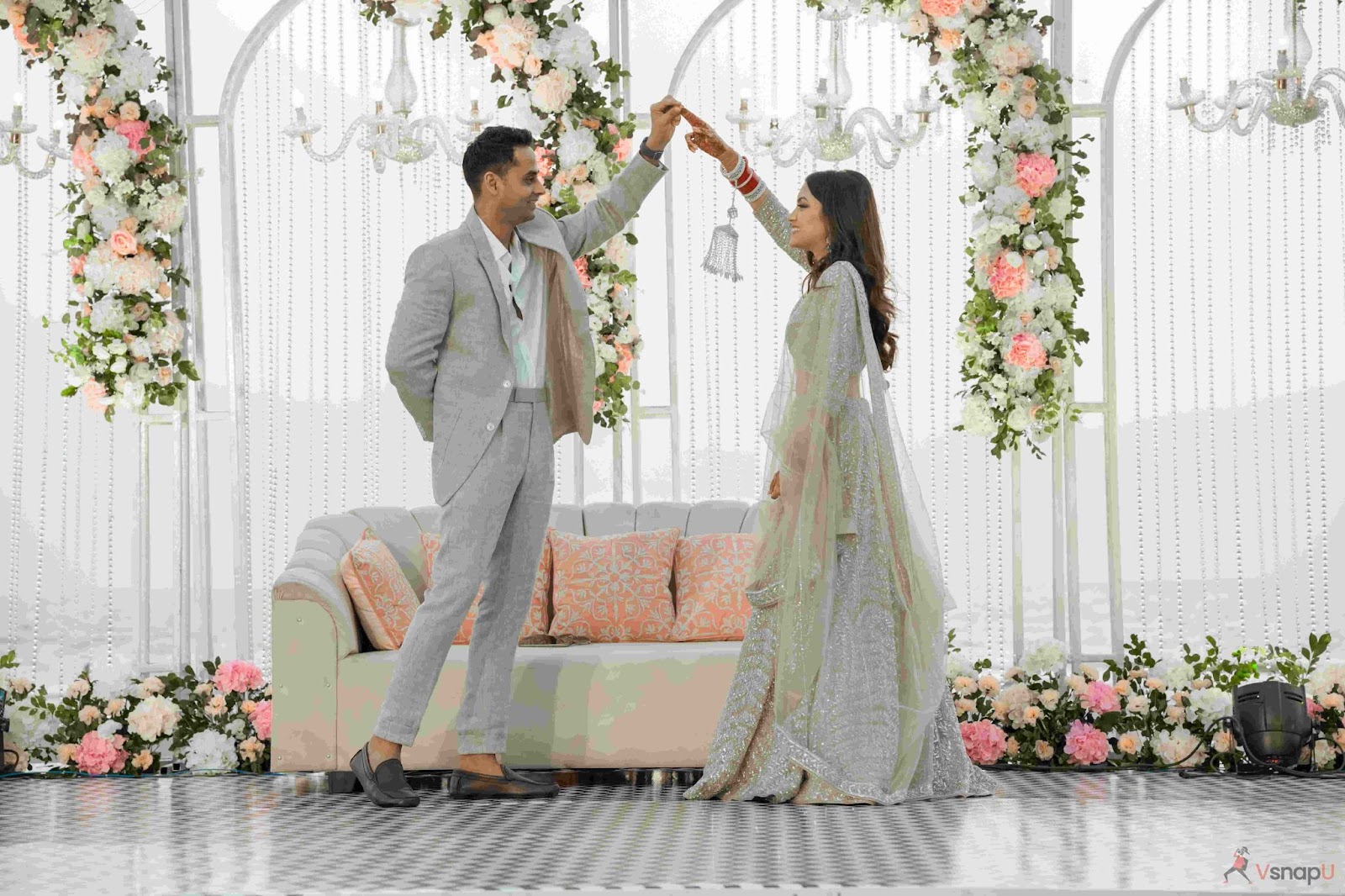 Groom dancing with bride on stage, capturing a candid and joyful moment at their Indian wedding.