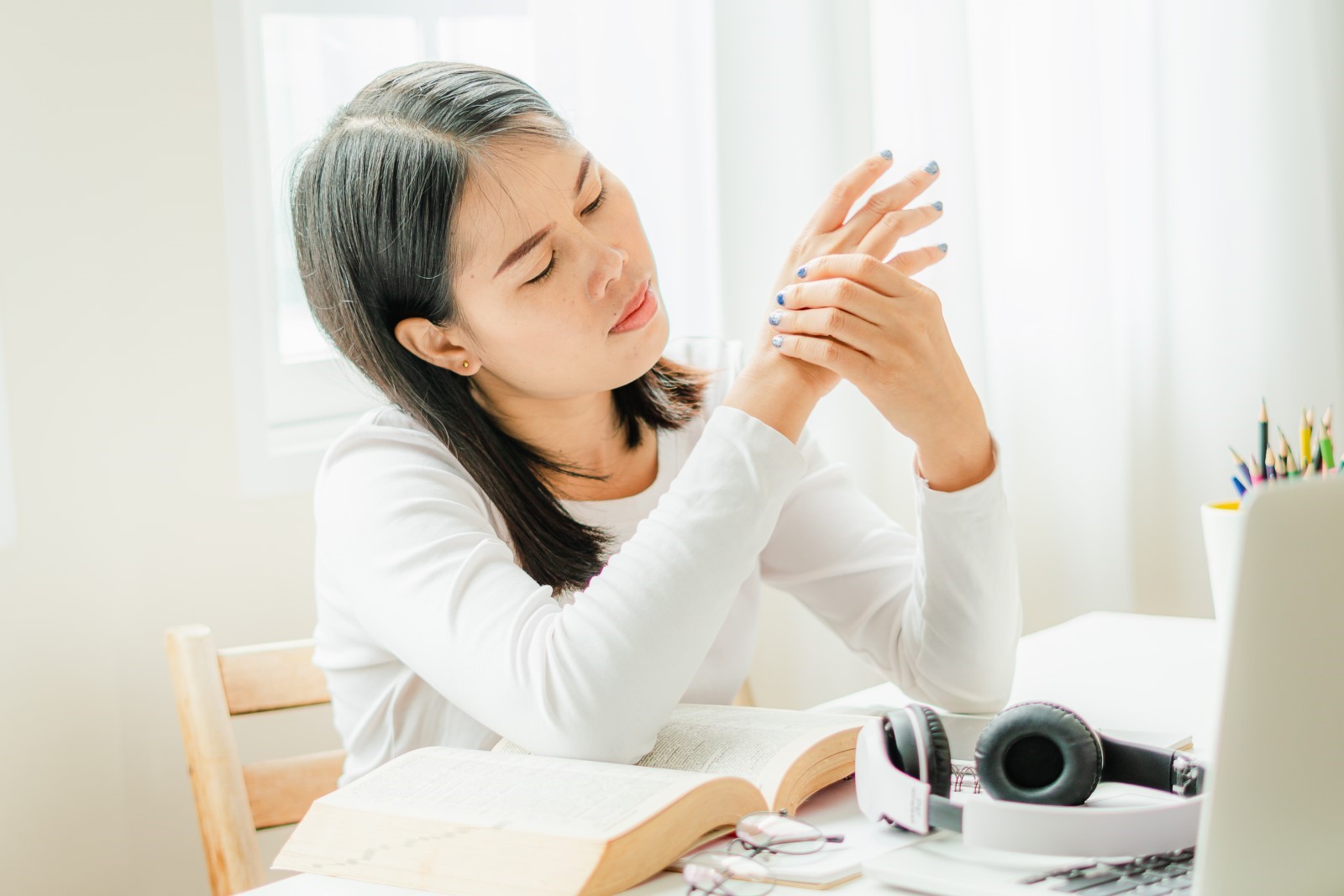 Alt Text: Woman sitting at her desk experiencing the connection between neuropathy pain and anxiety 