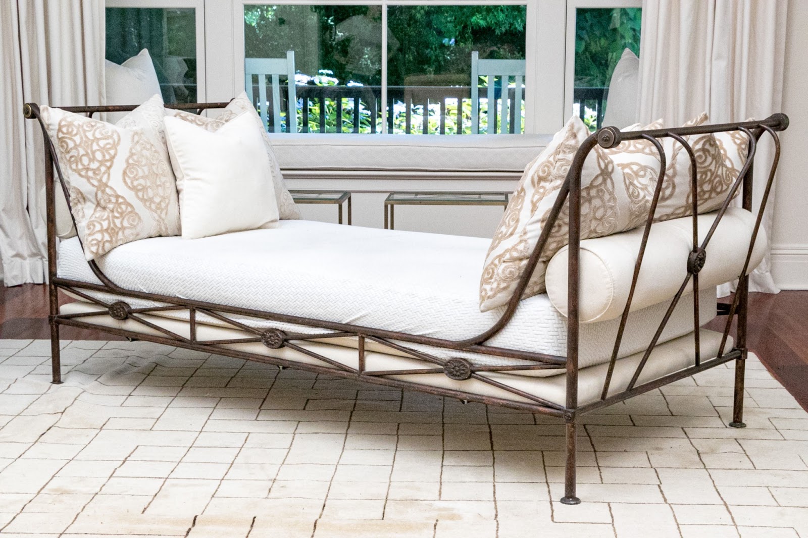 A pair of creamy beige upholstered slipper chairs with small white bolster-style pillows