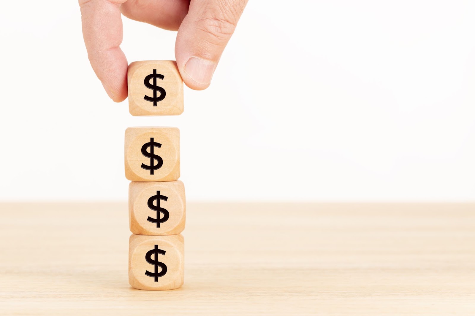 Person stacking wooden dies with money symbols on them. 