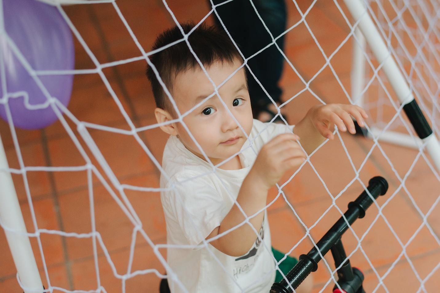 A child standing behind a net

Description automatically generated