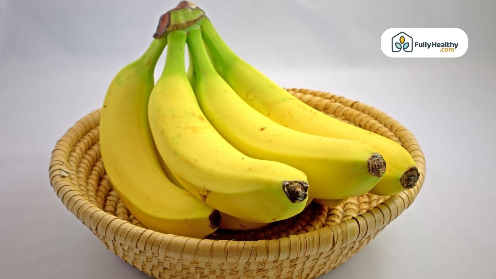 Ripe bananas in a woven basket on white background