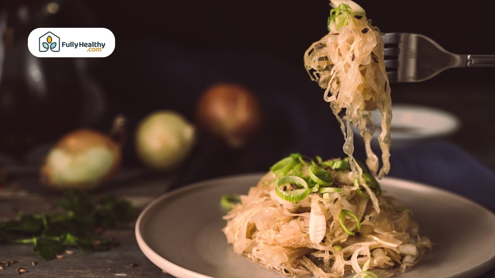 Fork lifting Sauerkraut from plate topped with chopped green onions.