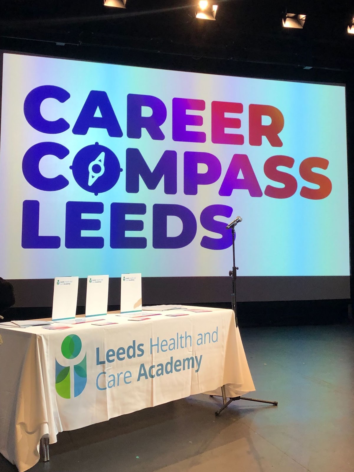 Large screen reads Career Compass Leeds. Table in front has banner reading Leeds Health and Care Academy