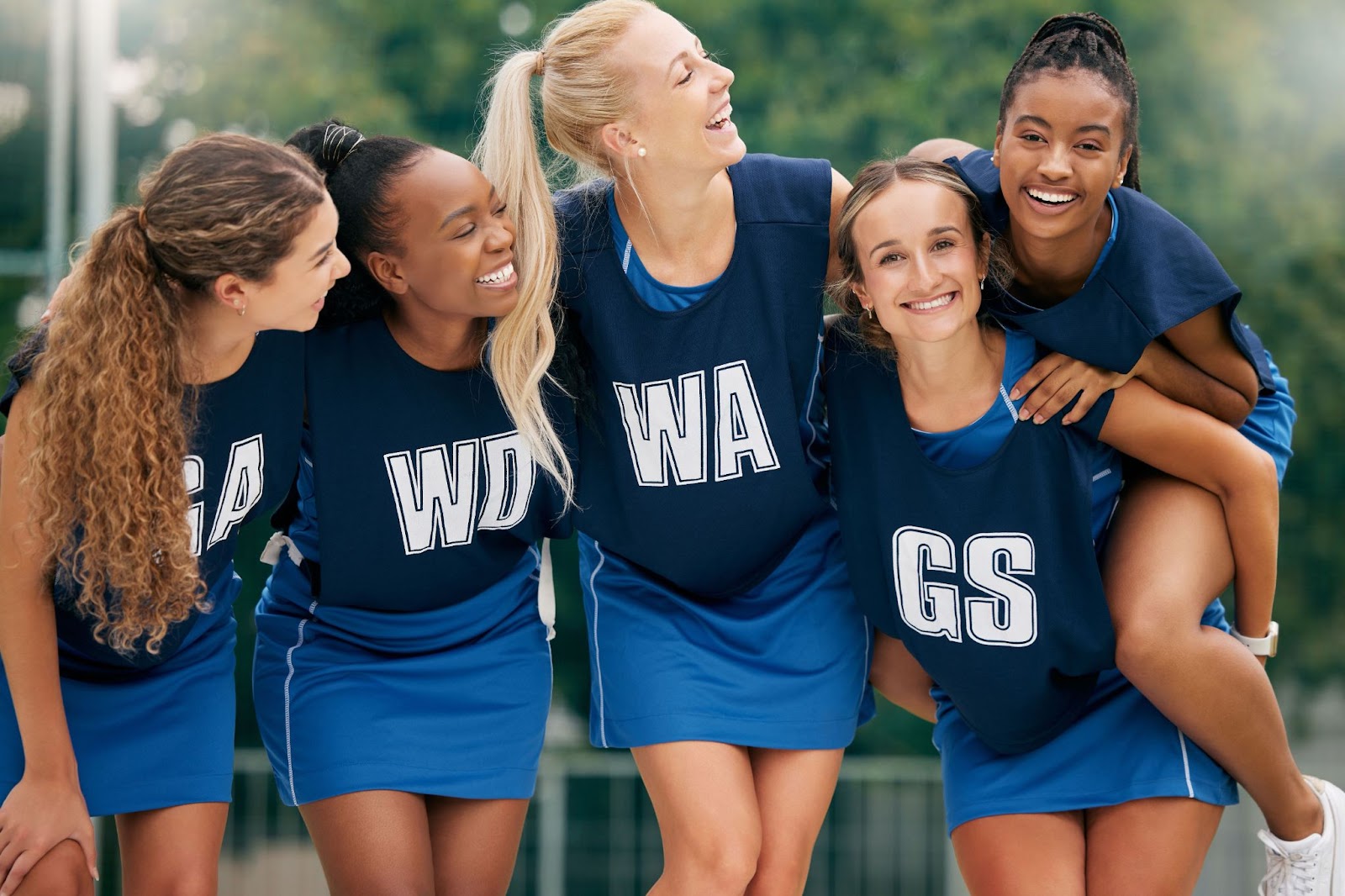 netball players happily being photographed wearing their uniform dress