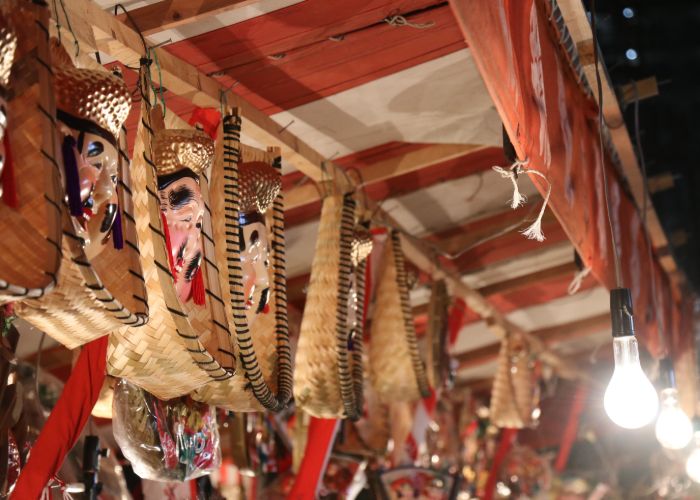 Lucky baskets adorned with the face of ebisu hang from the ceiling of a festival stall