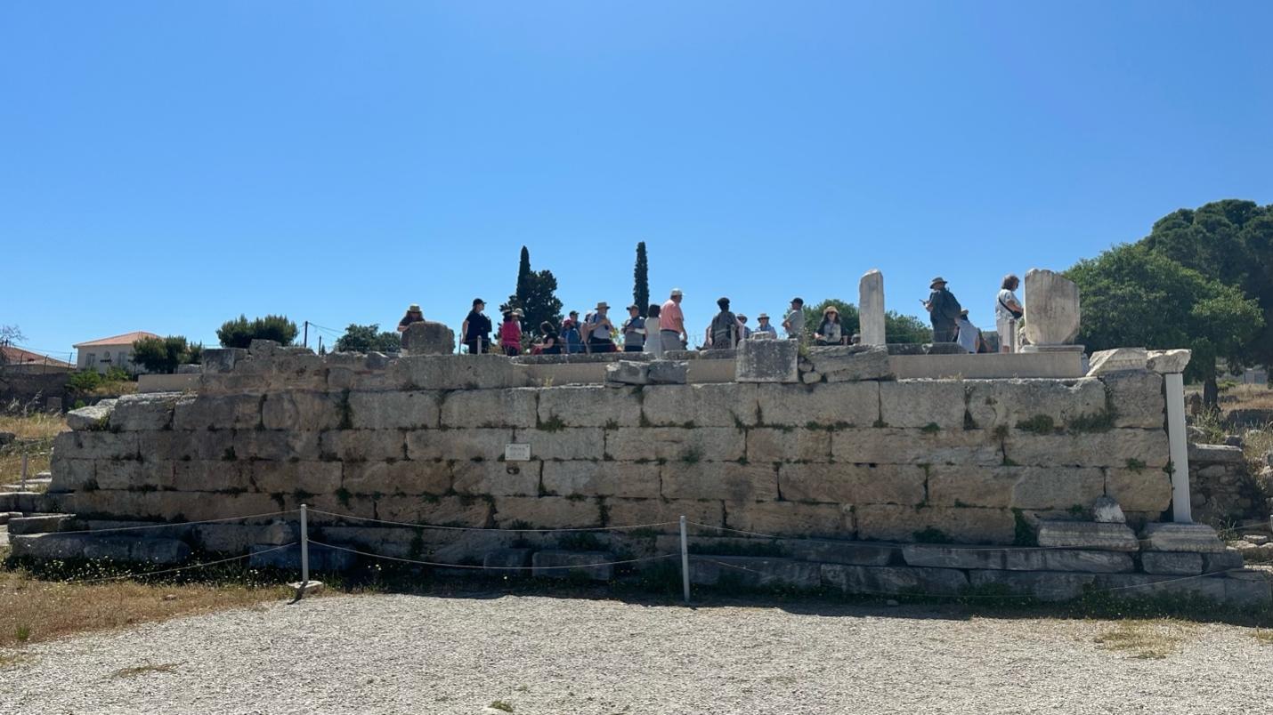 A group of people standing on a stone wall

Description automatically generated