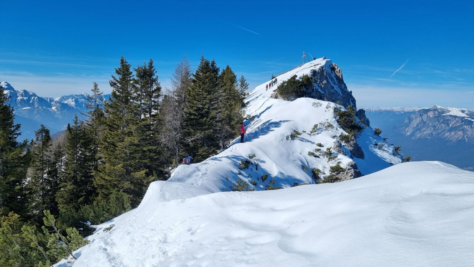 A snow covered mountain top with trees and people on it

AI-generated content may be incorrect.