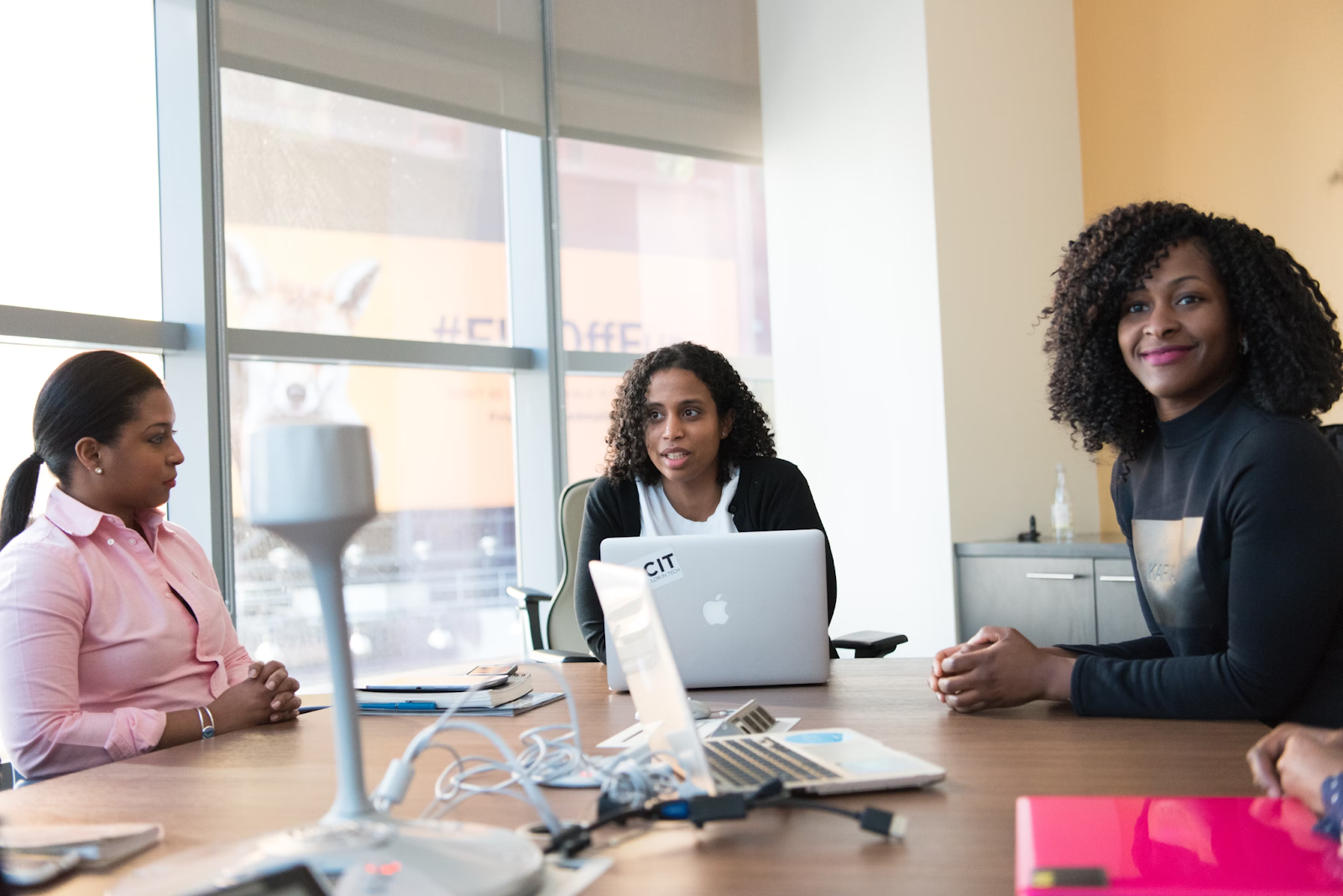 Photo de trois femmes assises à un bureau. Elles animent une réunion de travail.