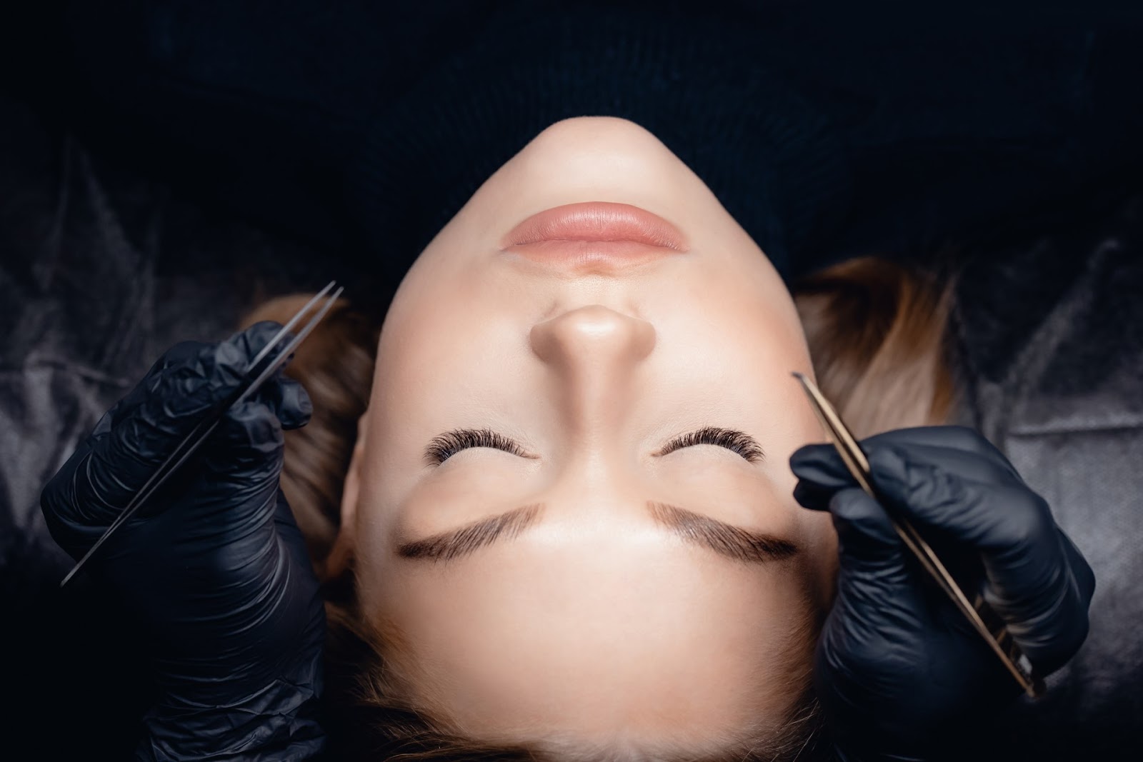 Close-up of a woman receiving affordable lash extensions at iLuxx Beauty Co. in Meridian, Idaho, with a focus on precise application by a trained technician.