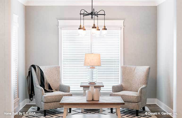 Sitting room with gray armchairs and wooden tables sitting on a patterned area rug.