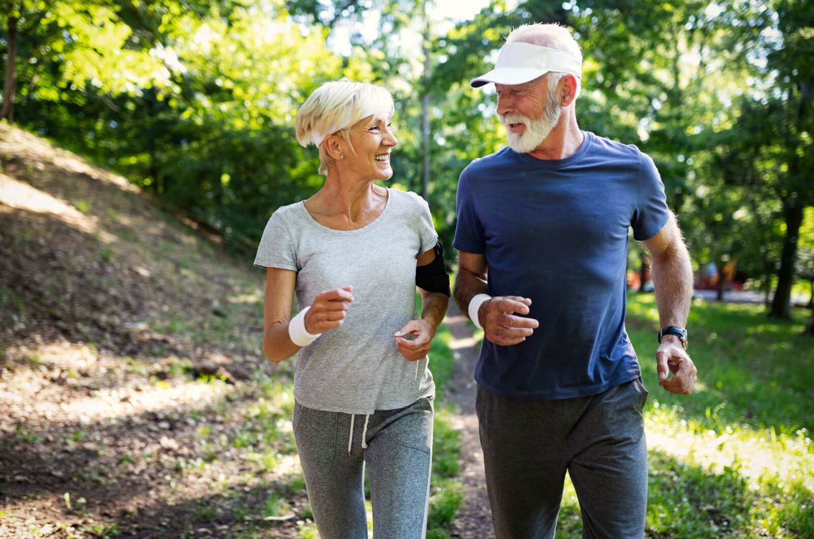 A happy older couple looking at each other while jogging outdoors.