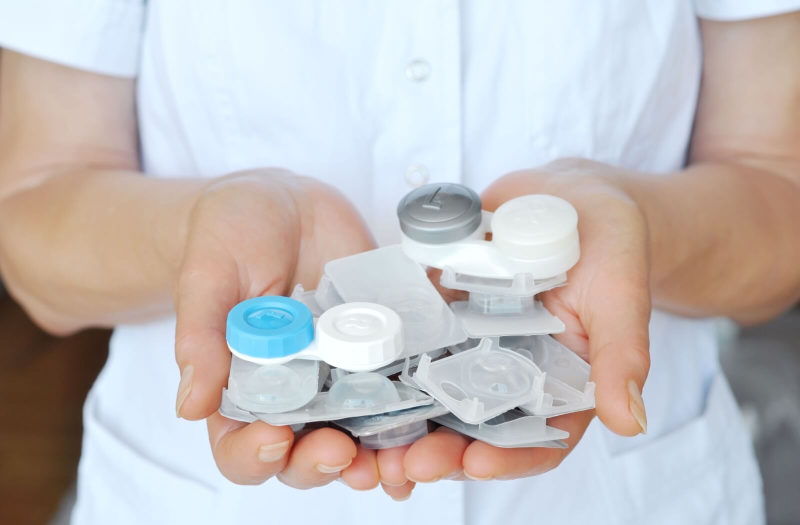 A doctor holds a collection of various types of contact lenses in the palms of their hands.
