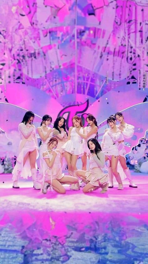 This contain TWICE' on stage in front of a large butterfly backdrop with pink lights