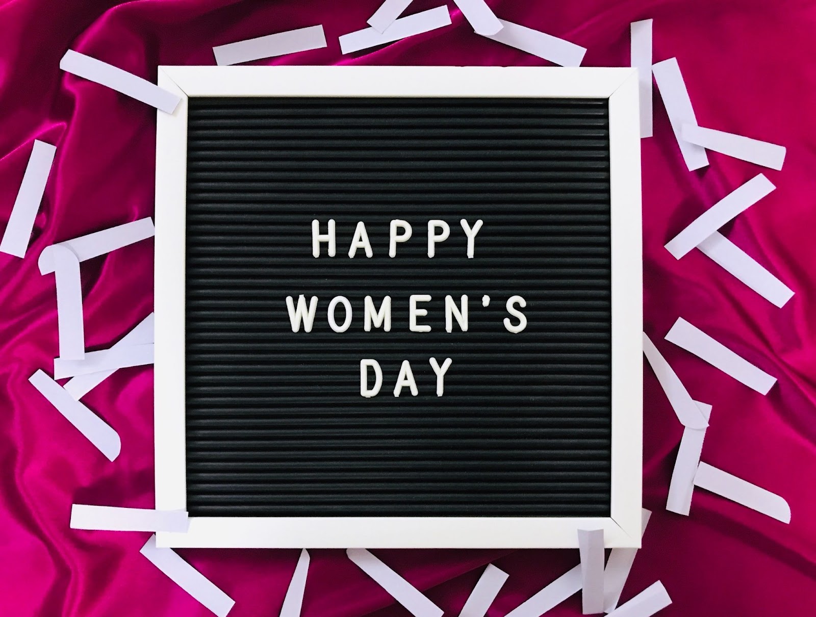 "Happy Women's Day" Sign on pink background with confetti