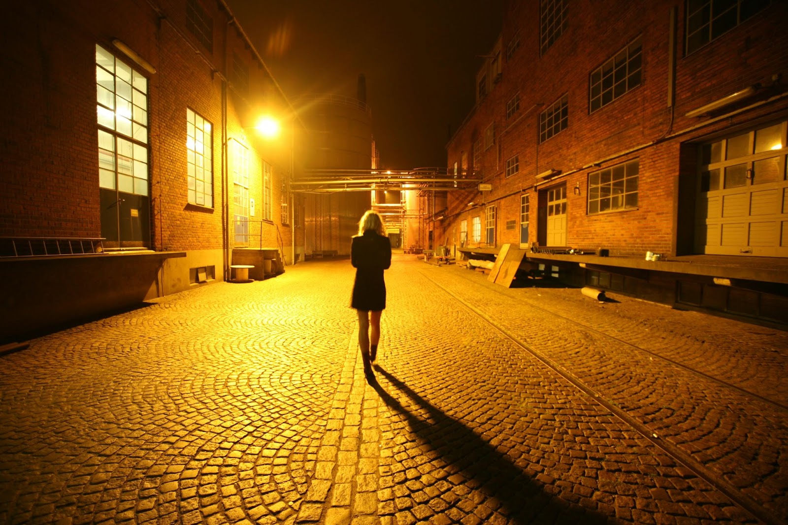 A worman walking in a dimly lit street at night