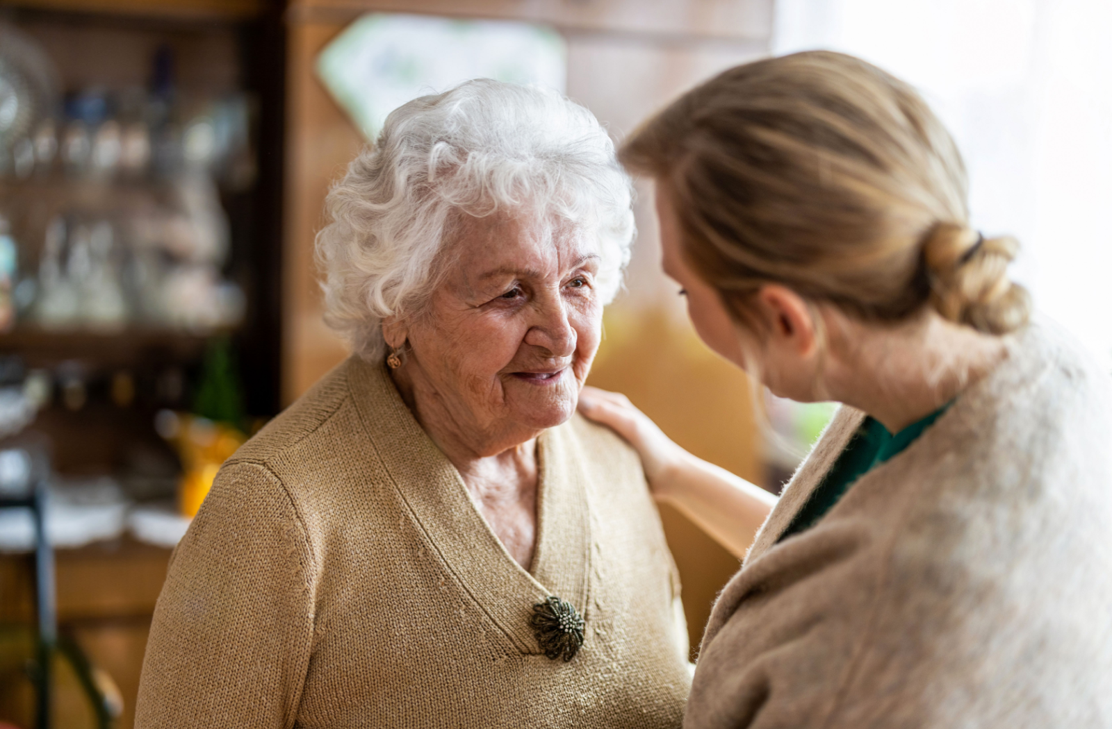 An adult child comforts their senior parent at their senior living community.