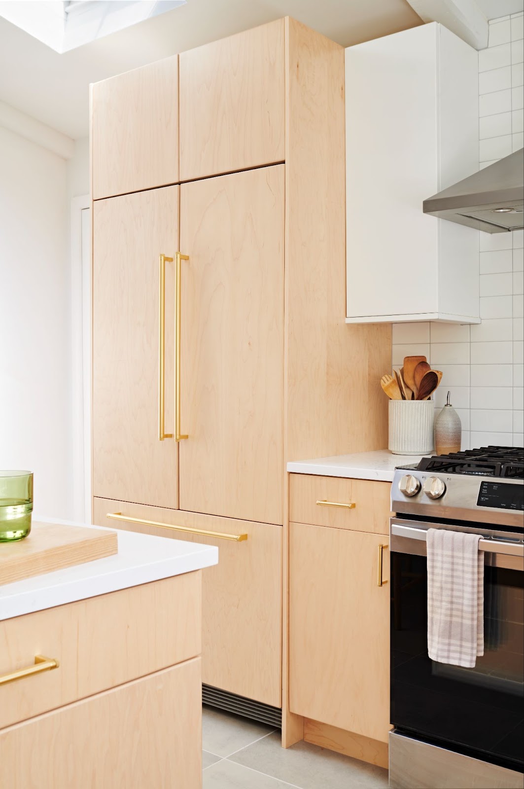 Kitchen with french door hidden fridge panel that matches maple wood cabinets.