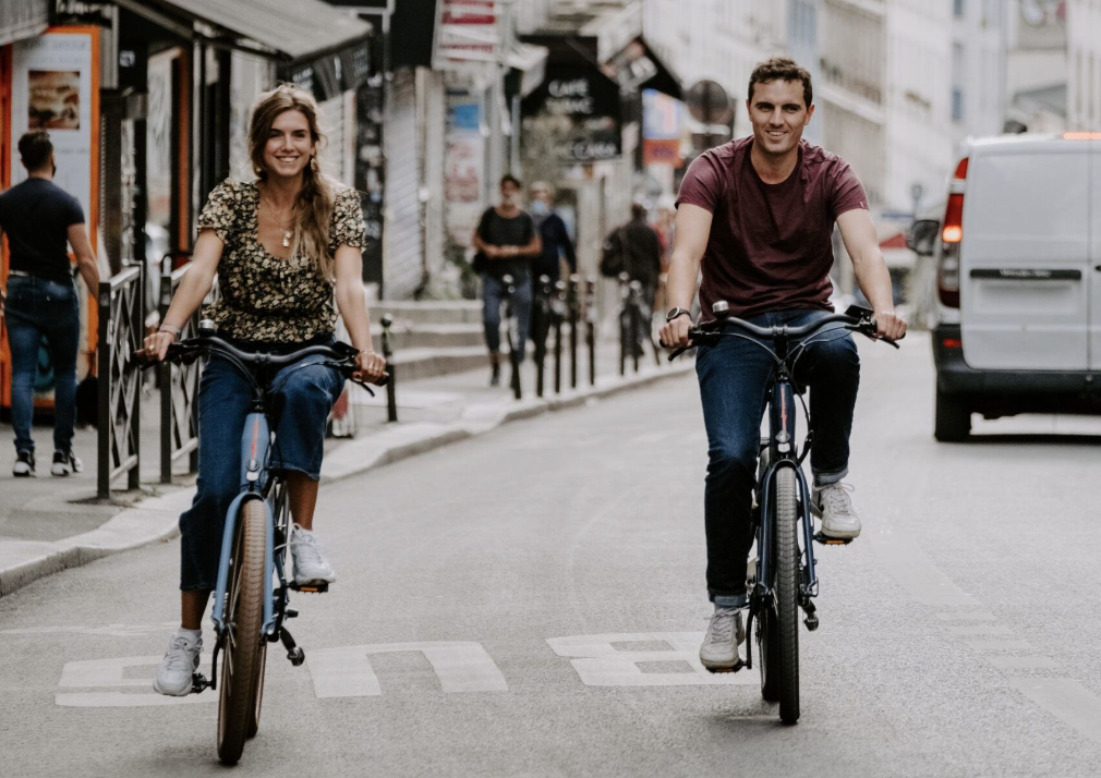 A woman and a man riding a OneBike rental electric bike in Paris