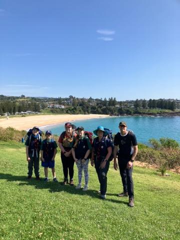 A group of people standing on a hill by a body of water

Description automatically generated