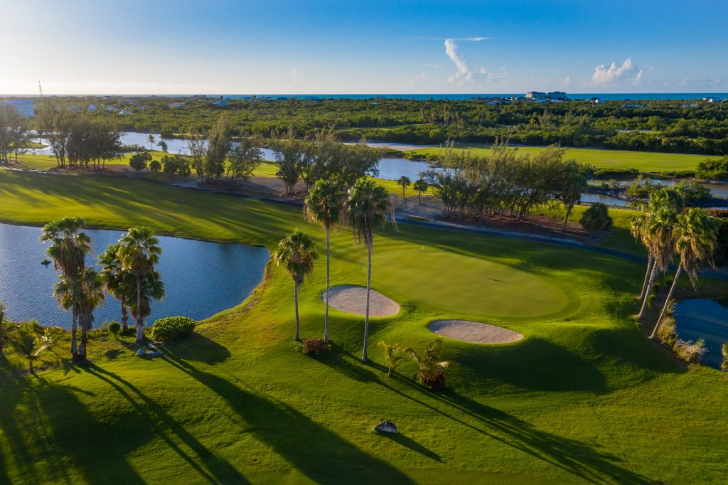 Serenity at the Royal Turks & Caicos Golf Club Alt text: Immaculate aerial views of the golf course at Royal Turks & Caicos Golf Club, dotted with palm trees, ponds, and meticulously maintained sand bunkers.  