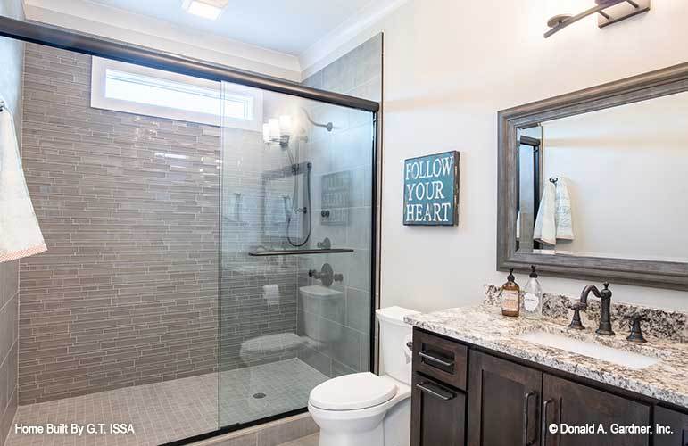 Another bathroom wtih a sink vanity, a toilet, a nd a walk-in shower accentuated with linear mosaic tile backsplash.