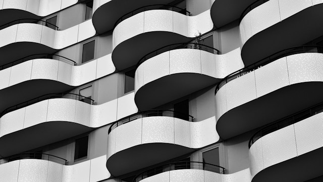 Black and white photo of a modern building façade featuring a pattern of wavy, protruding balconies. The parametric design showcases contemporary architectural style.