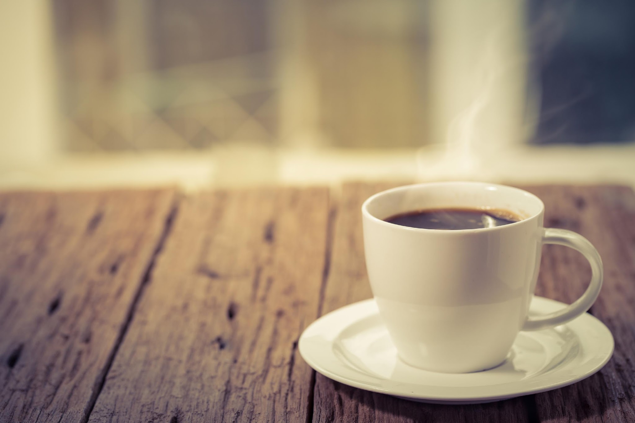 Black coffee in a white cup on a wooden table