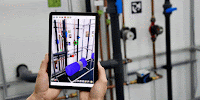 a person is holding a tablet in front of pipes and a wall with the letter r on it (provided by Tenor)